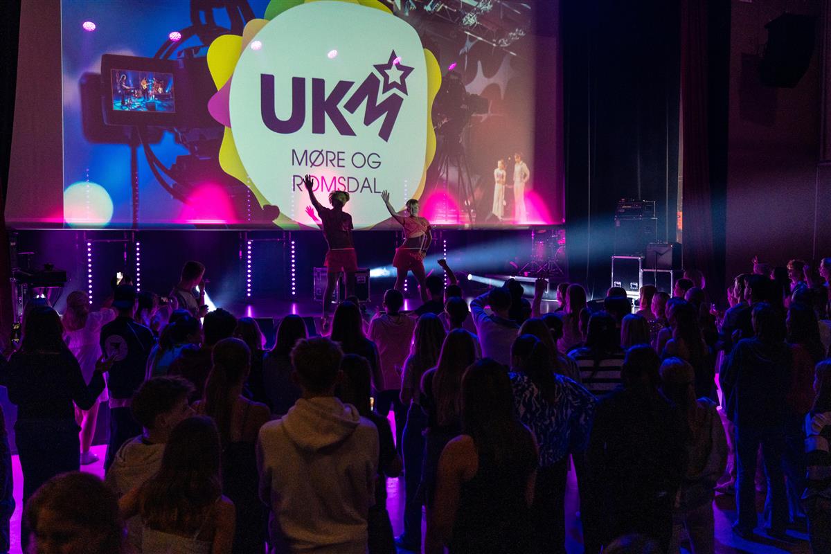 Bilde fra UKM fylkesfestival. Det er bilde av to artister på scena med mye publikum. - Klikk for stort bilde